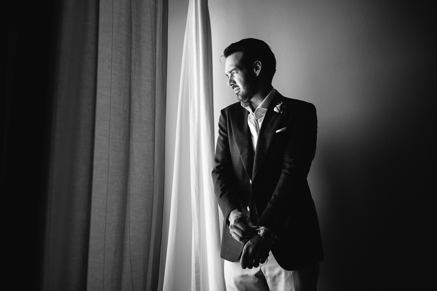 groom getting ready in front of window