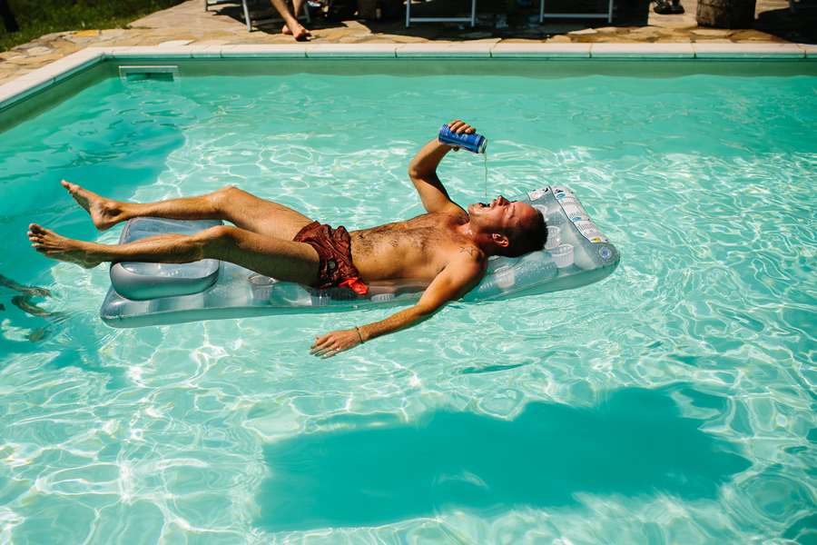 wedding guest drinking beer in pool in tuscany