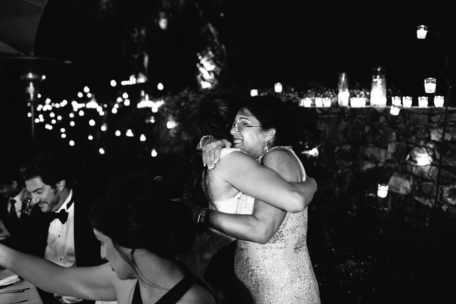 bride hugging her mom during wedding dinner